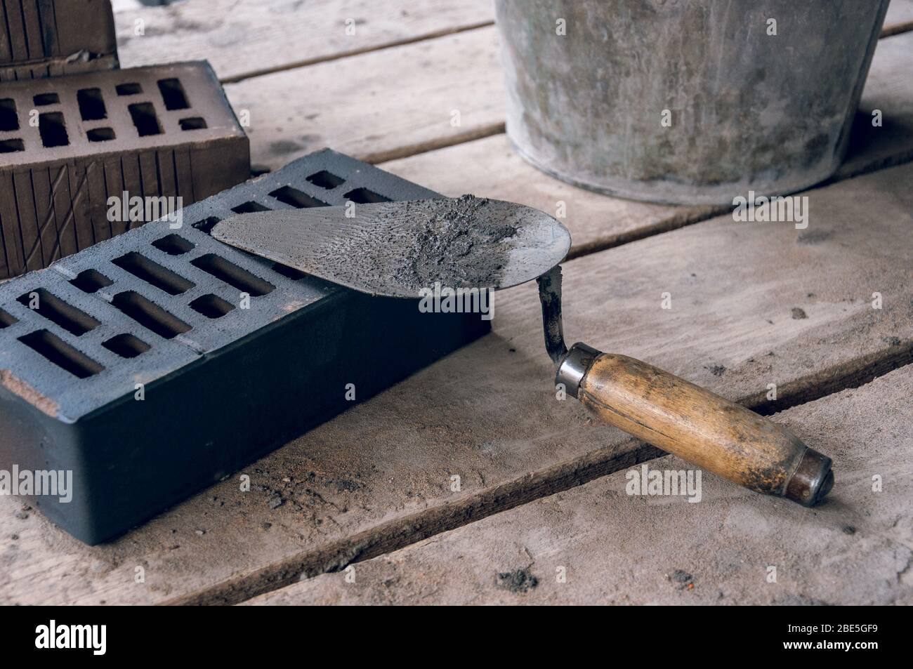 A mason tool by a stern plan in the workplace. Trowel for bricklaying. Construction mason cement