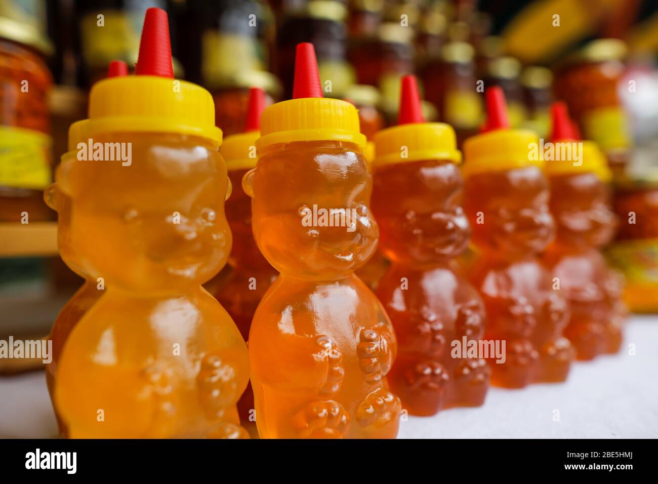 Bee honey in plastic bear shaped bottles on display in a market. Stock Photo