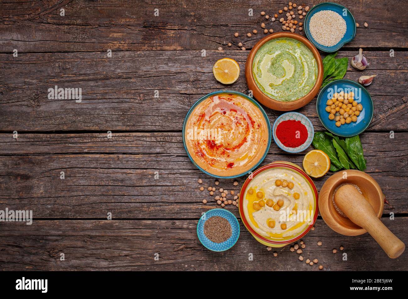 Colorful hummus bowls, healthy vegan dips on a brown wooden wooden