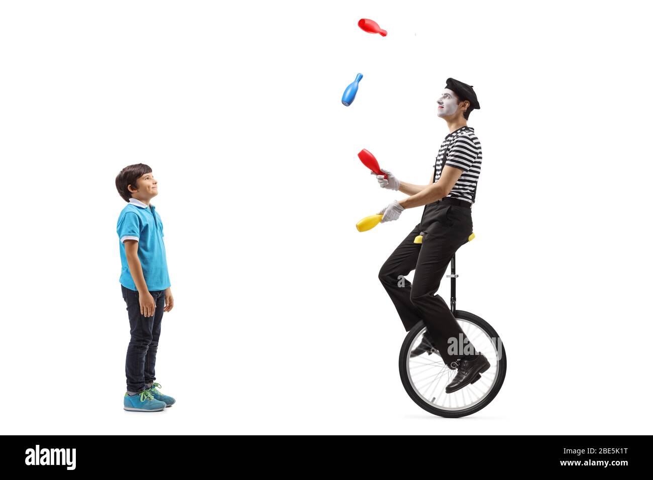 Full length profile shot of a boy watching a clown juggling on a ...