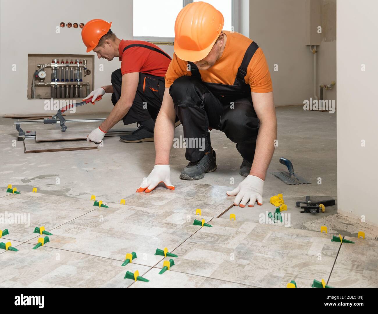 Two workers are installing ceramic tiles on the floor Stock Photo Alamy