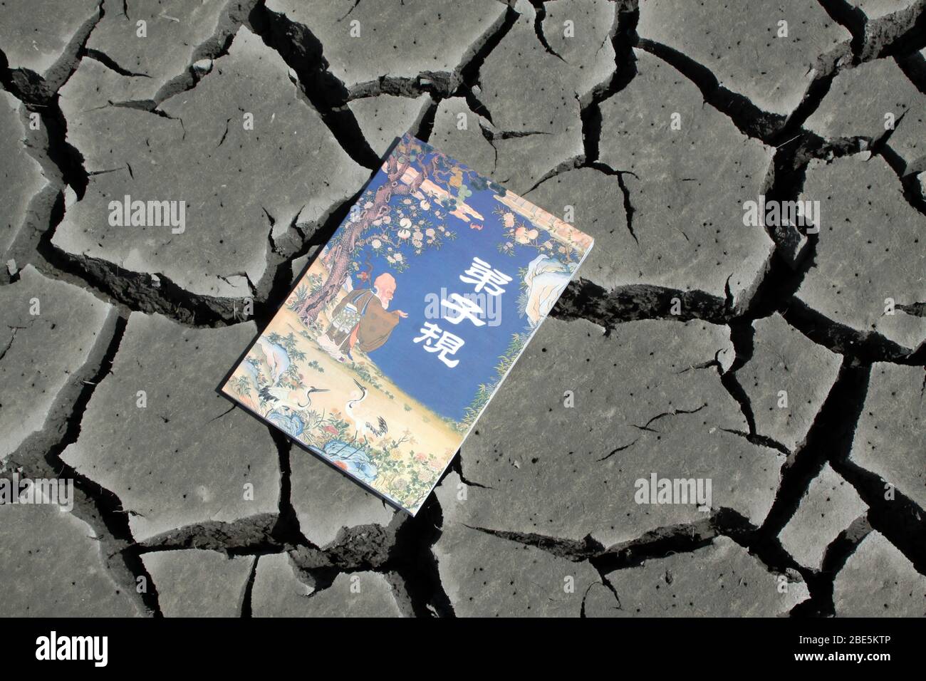 close up of a book in the dry land, creative images, metaphor of knowledge as spring water, as is indispensable to the people. Stock Photo