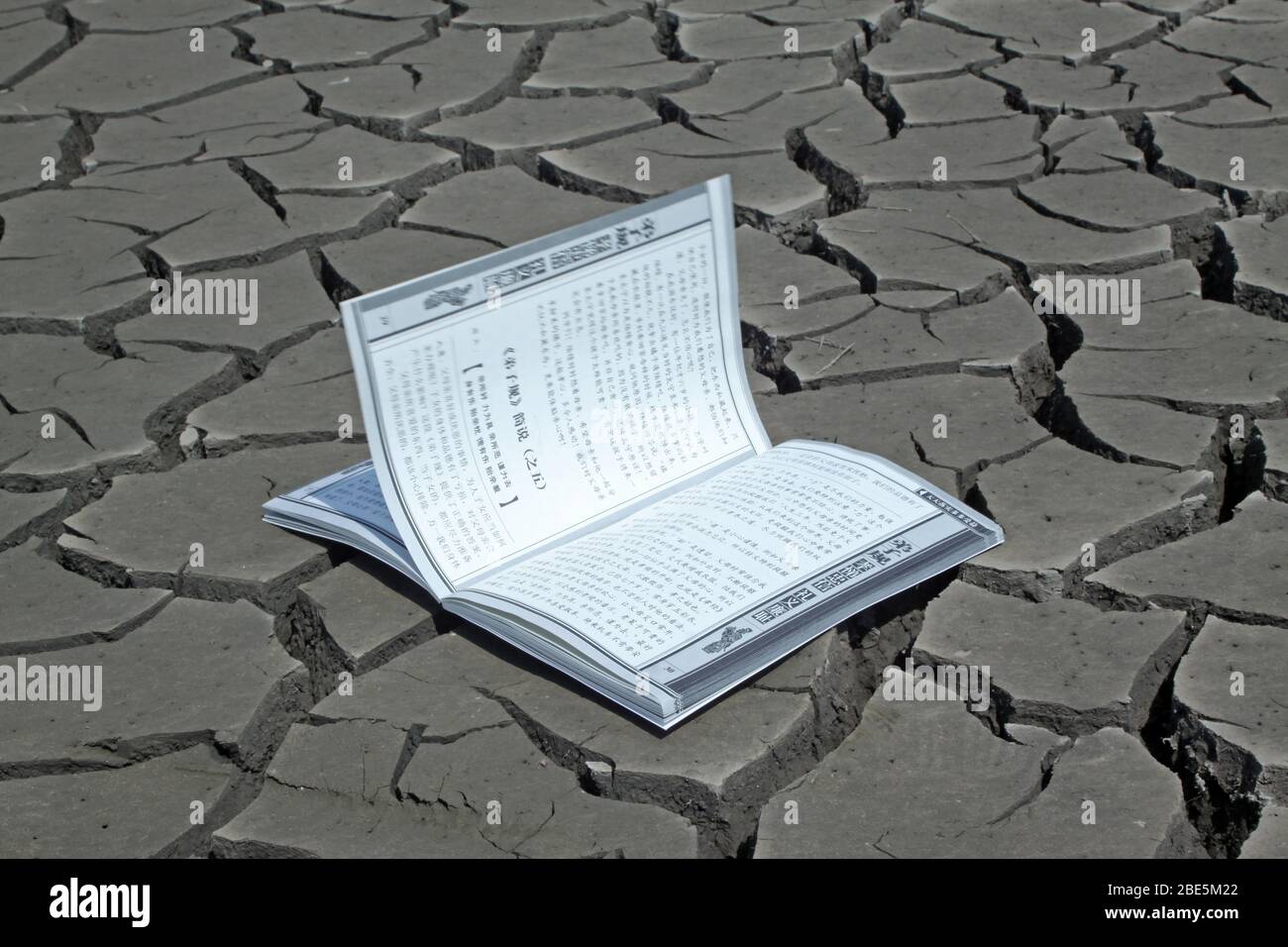 close up of a book in the dry land, creative images, metaphor of knowledge as spring water, as is indispensable to the people. Stock Photo