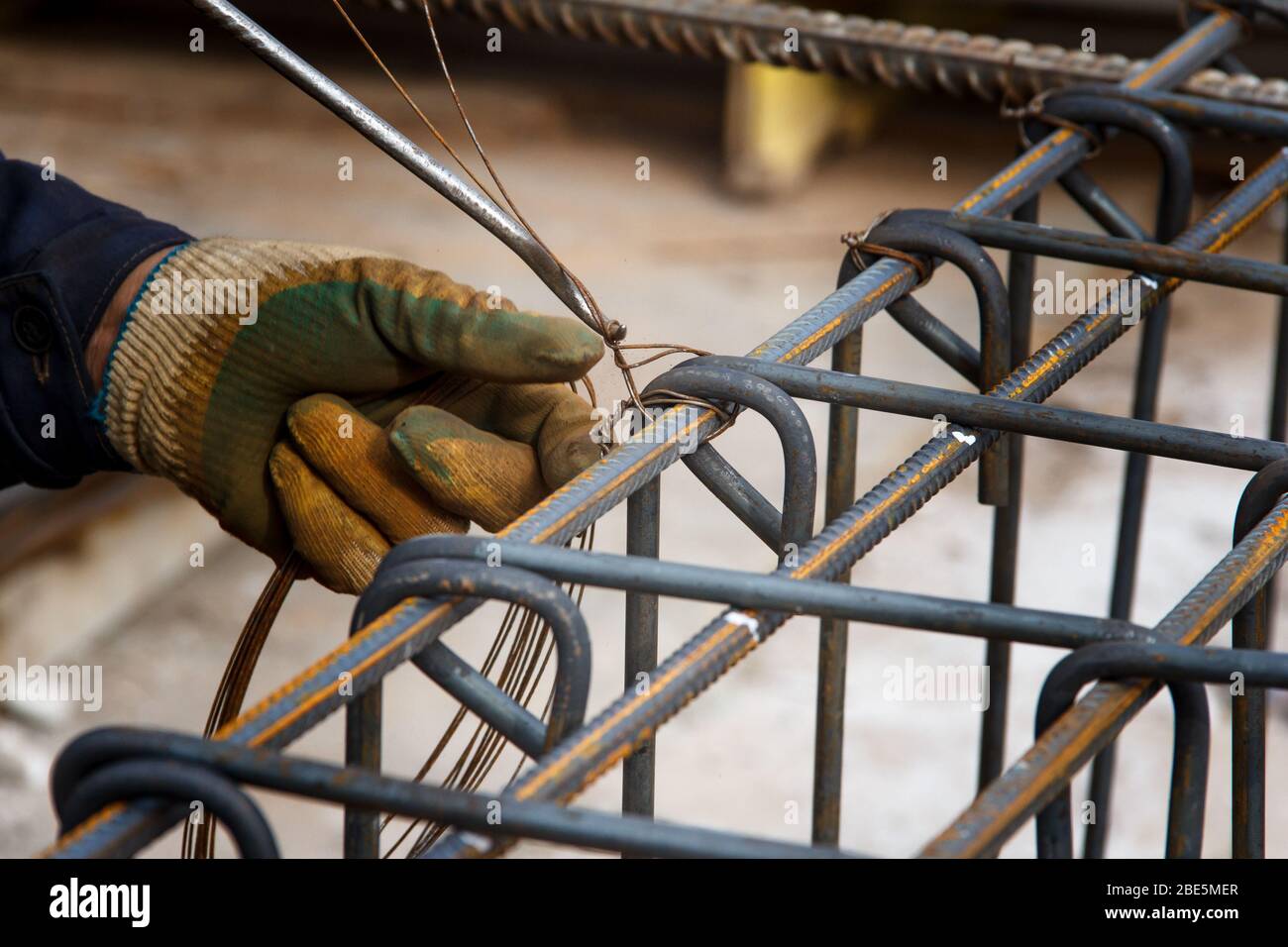 Assembly of reinforcing bars for pouring concrete. Construction worker fabricating steel reinforcement bars. Preparation for concrete work.Wire mounti Stock Photo