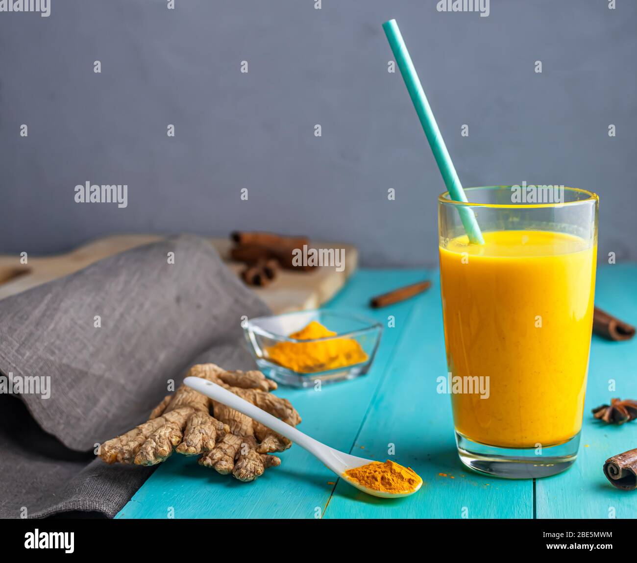 golden milk, milk with turmeric, spices. with a drinking tube. on a blue wooden background. with copy space Stock Photo
