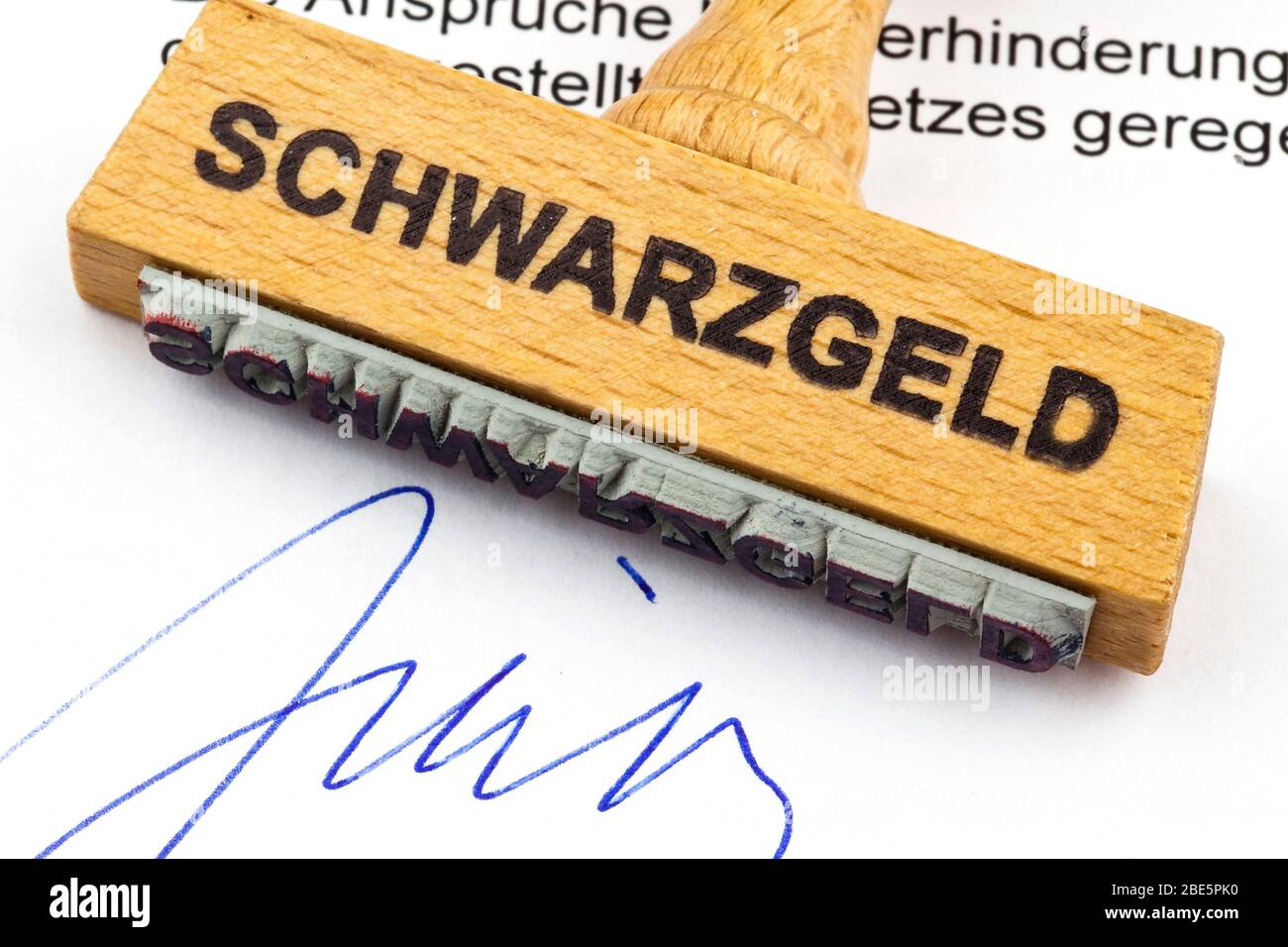 Ein Stempel aus Holz liegt auf einem Dokument. Deutsche Aufschrift: Schwarzgeld Stock Photo