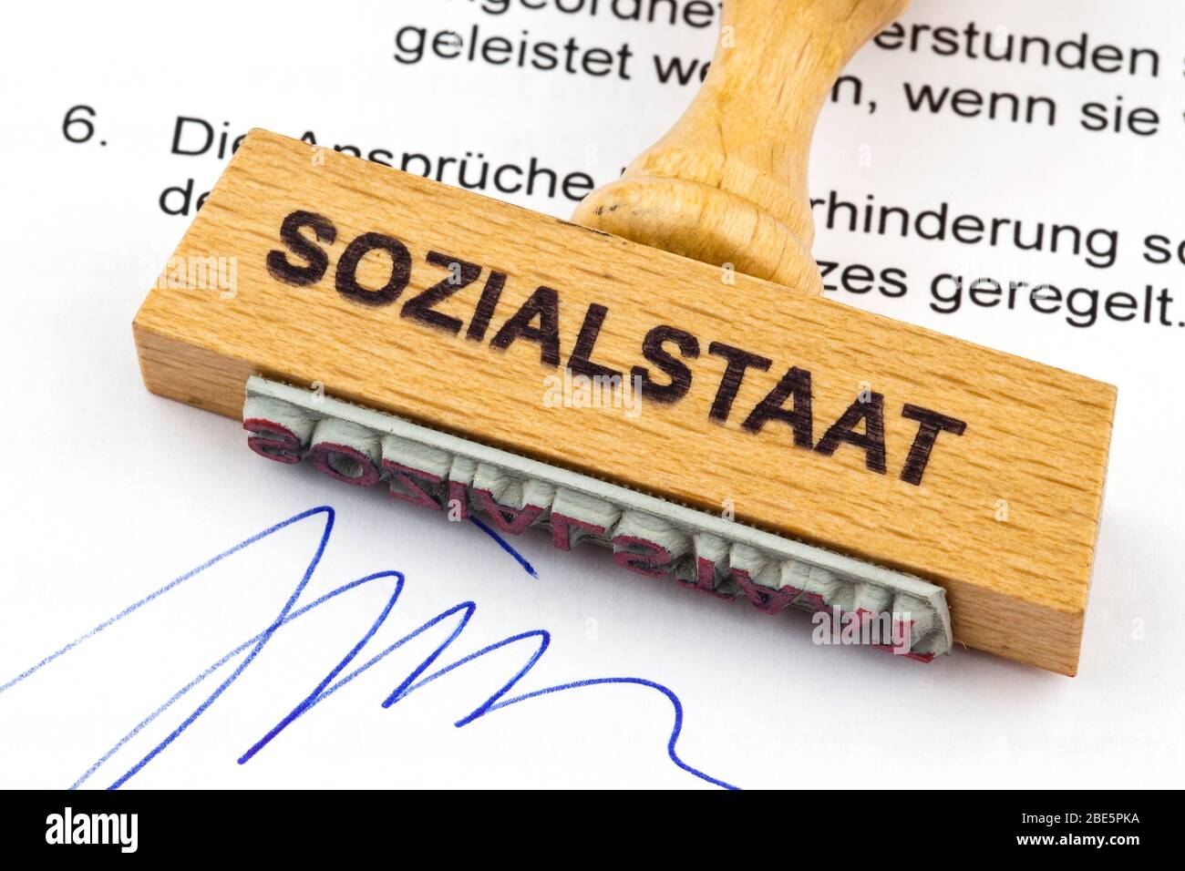Ein Stempel aus Holz liegt auf einem Dokument. Deutsche Aufschrift: Sozialstaat Stock Photo