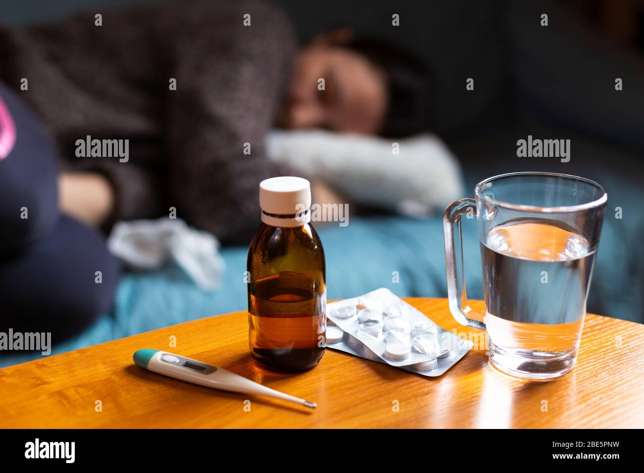 Woman feeling sick and have cramps lying on sofa and have some medicamentation on table Stock Photo