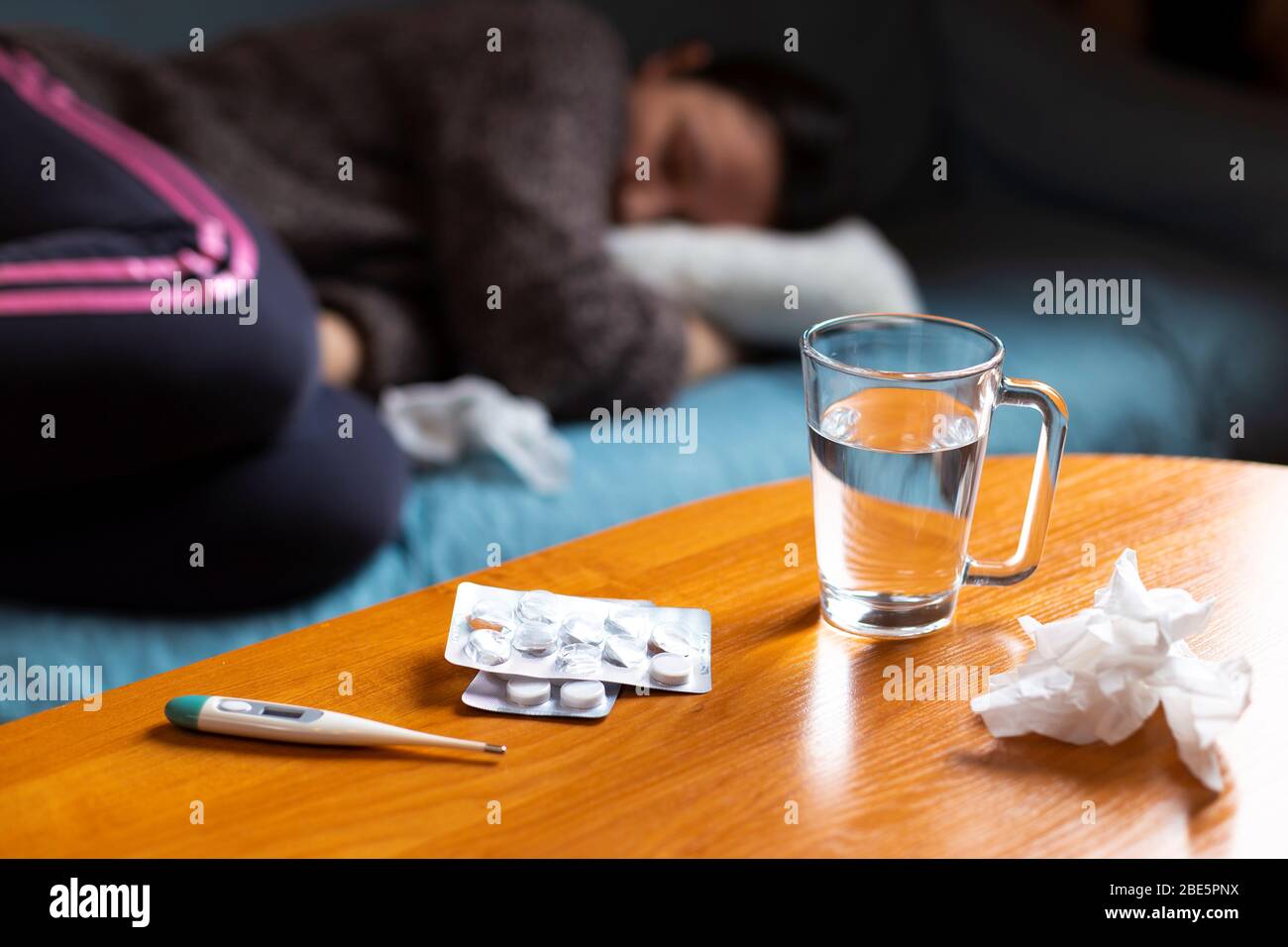 Woman feeling sick lying on sofa and have some medications on table Stock Photo