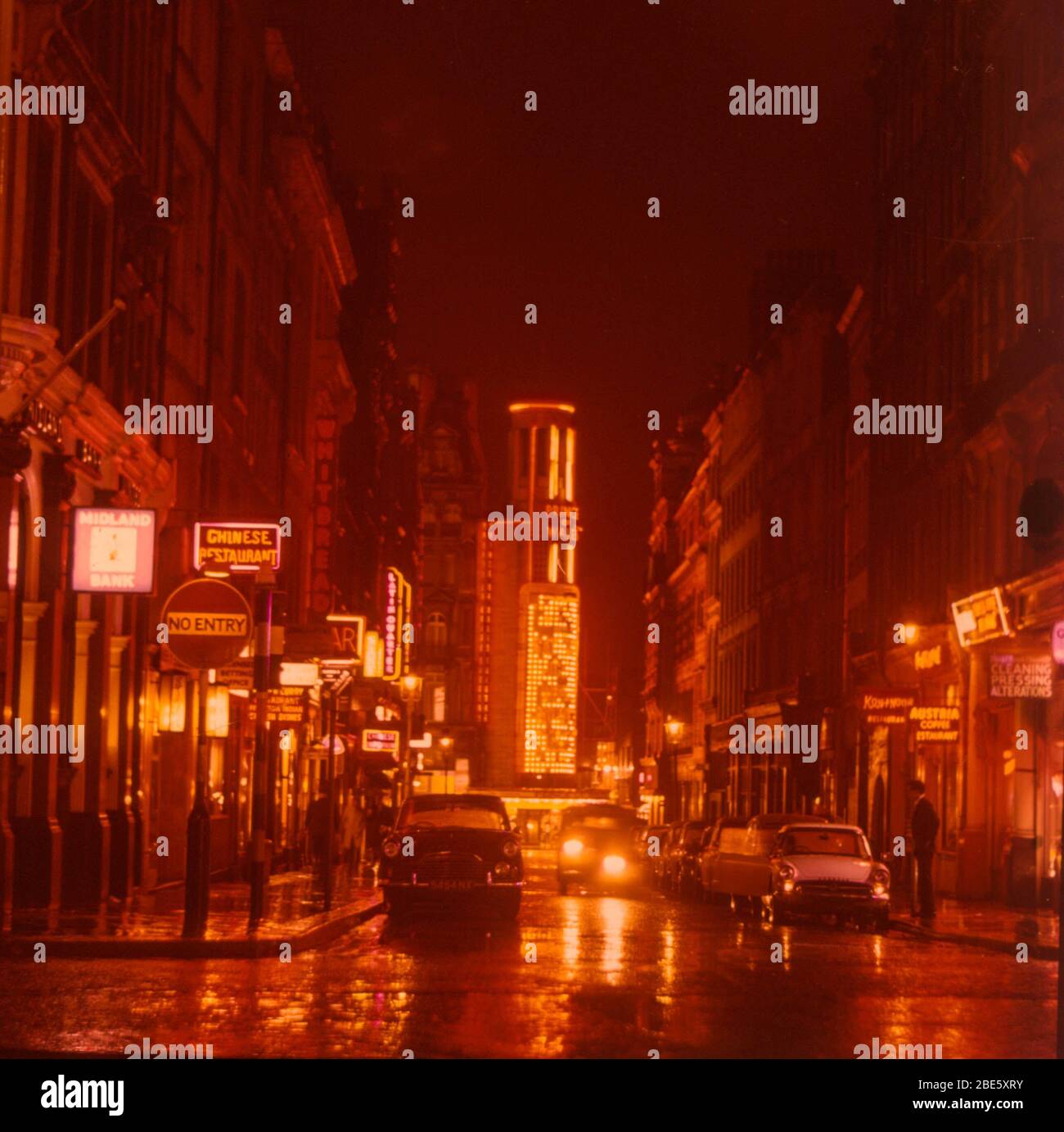 A shot taken in 1964 at night and in the rain, looking down Rupert Street in London's Soho with the Prince of Wales Theatre at the end and the neon lights reflecting in the puddles. Stock Photo