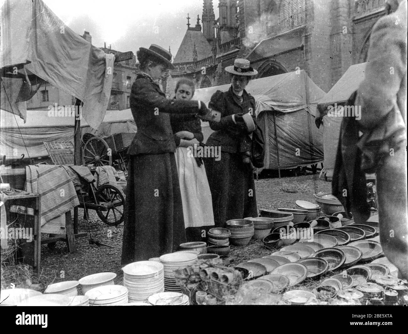 Two well dressed rich women shopping at a market stall in the town square of Dieppe in Normandy, France in the 1890s Stock Photo