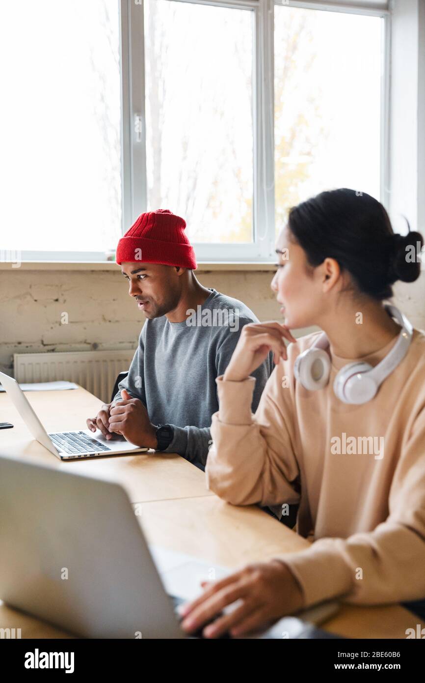 Image of a young concentrated multiracial colleagues indoors work in office with laptop computers. Stock Photo