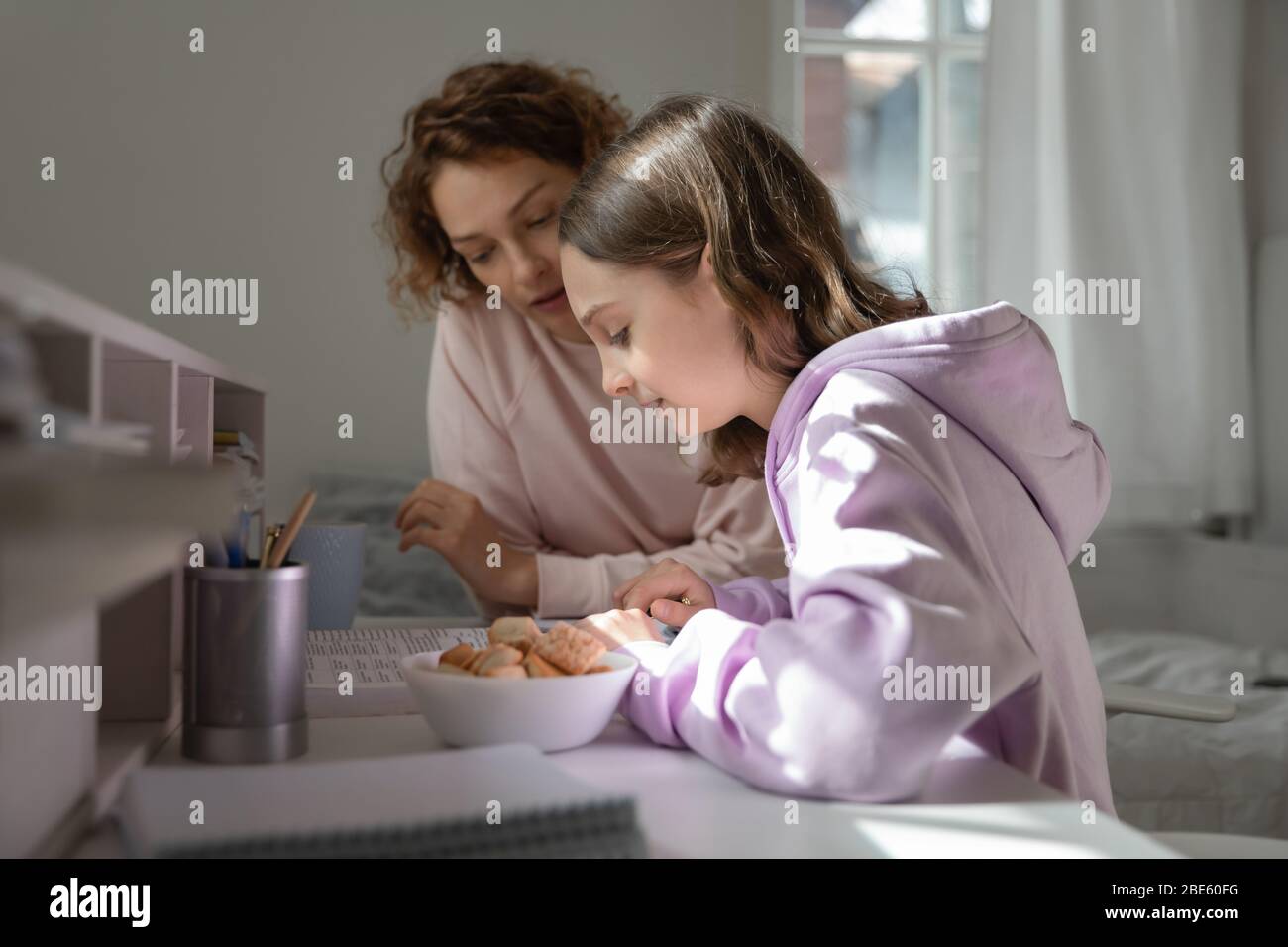 Focused mom helping teenage daughter doing homework studying from home Stock Photo