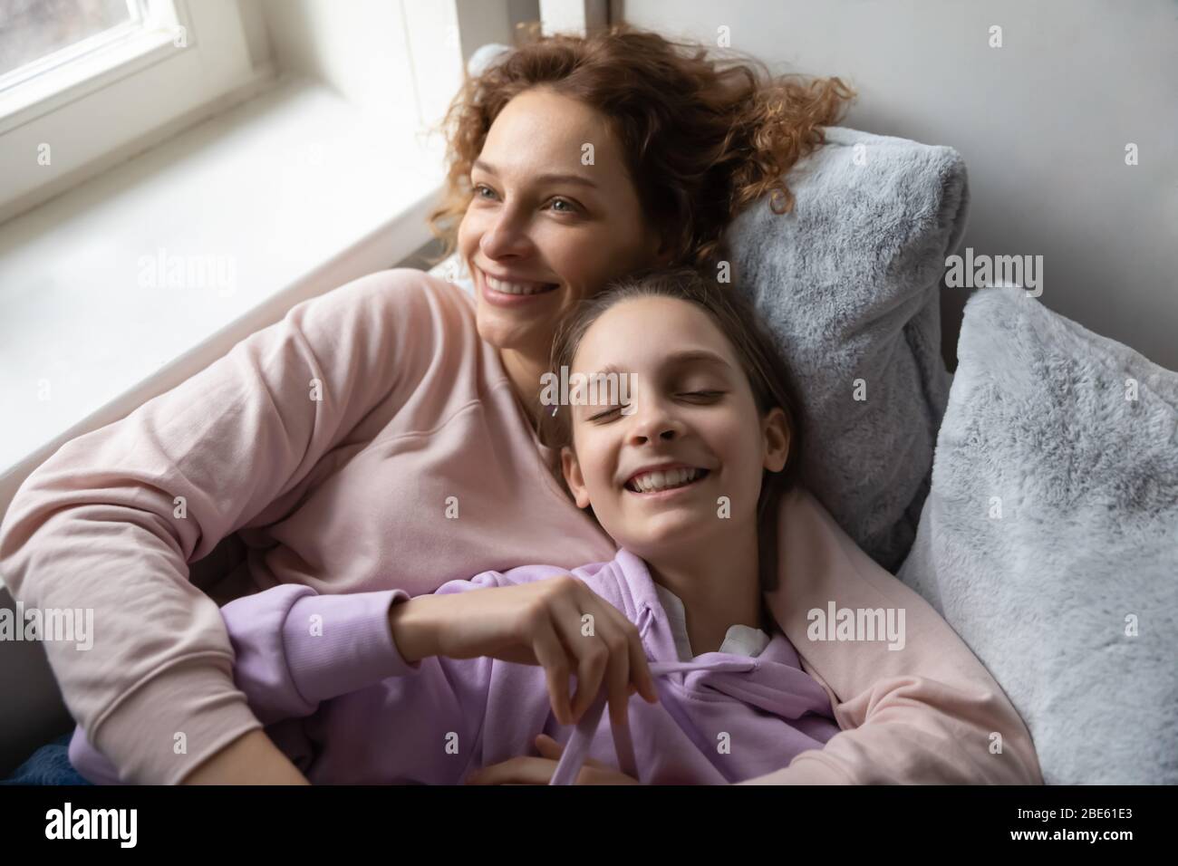 Relaxed affectionate mom and teenage daughter resting lying on bed Stock Photo