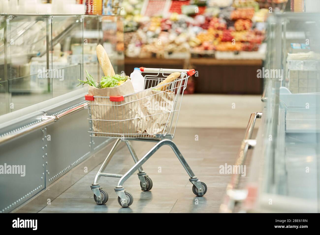 Full length background image of shopping cart with groceries standing in supermarket, copy space Stock Photo