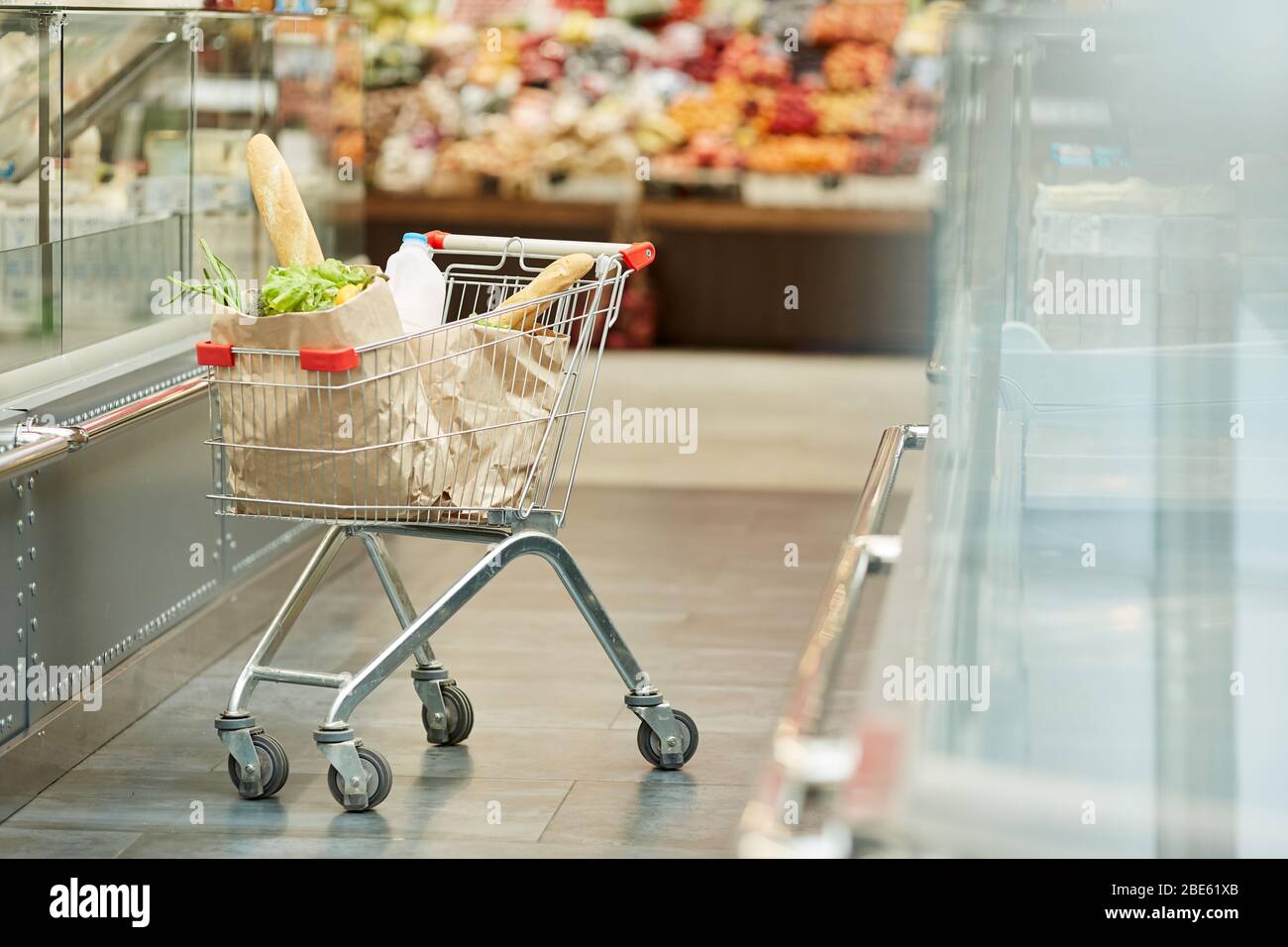 Background image of shopping cart with fresh groceries standing in supermarket isle, copy space Stock Photo