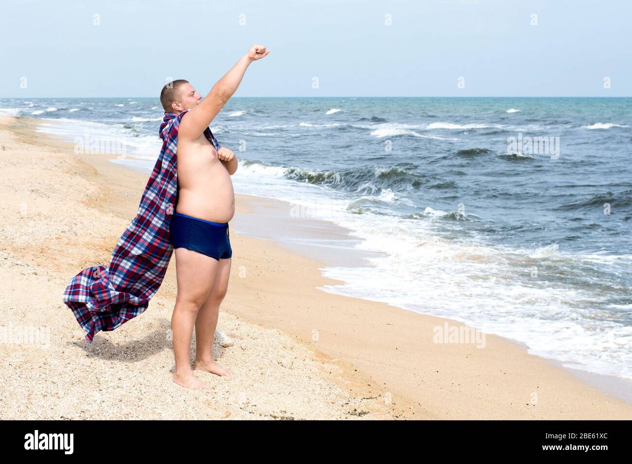 Fat superhero stands on the shore of the sea Stock Photo