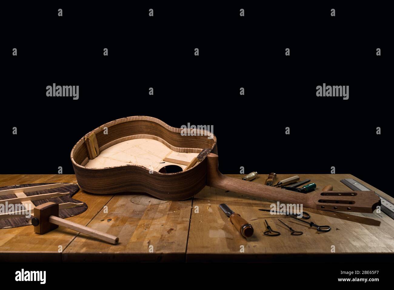 Dark still life of luthier workbench, guitar build. Spanish classic
