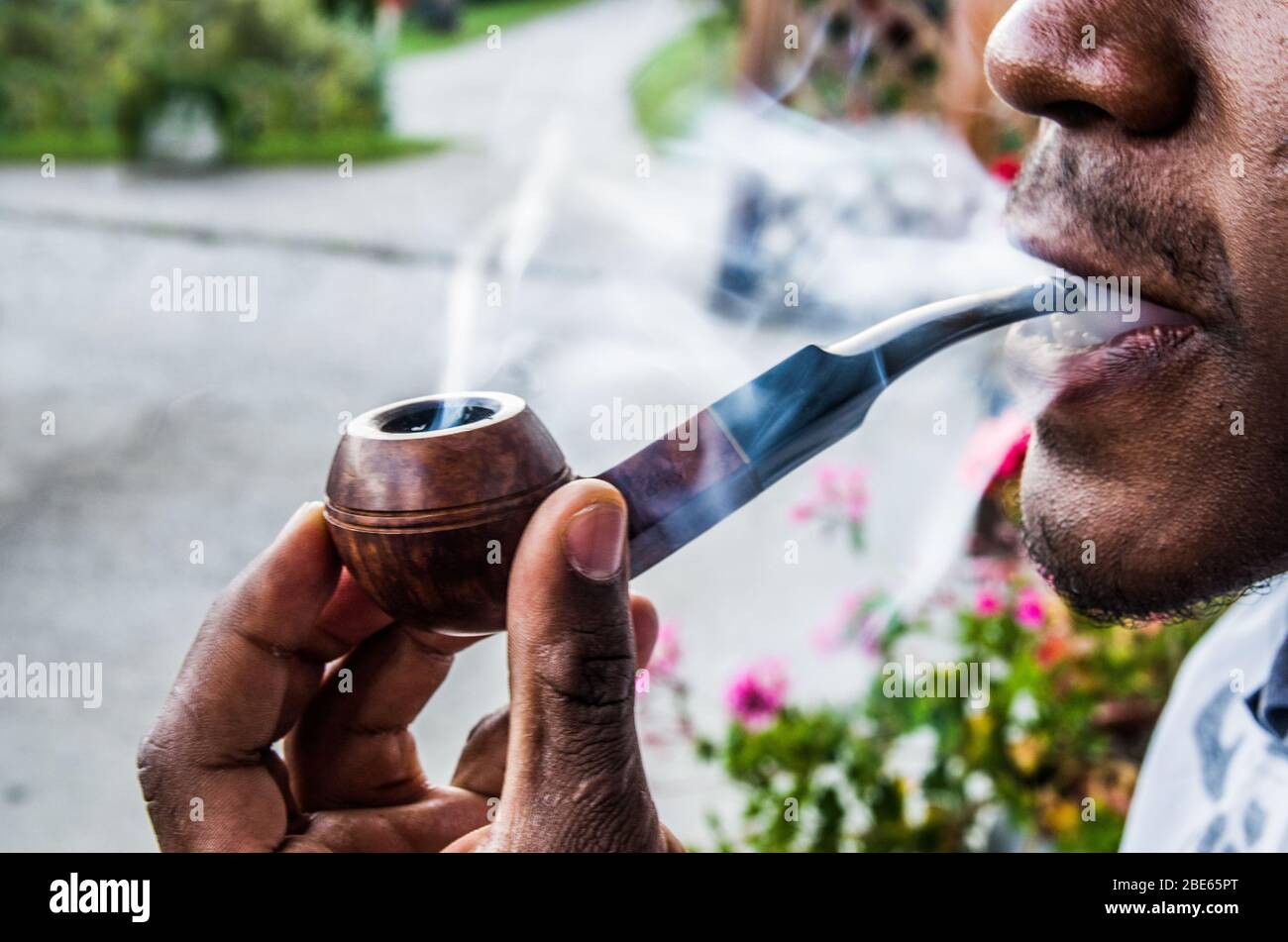happy tobacco happy young man smokes with pleasure the tobacco in his pipe among sweet  swirls and clouds of smoke Stock Photo