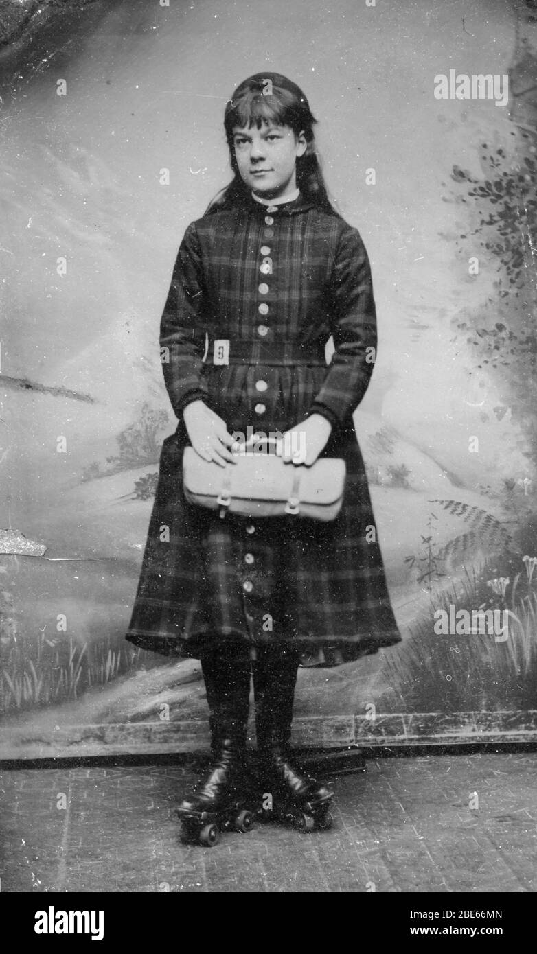 Roller Skates - a happy girl posing with her fine roller skates clamped to her high-button shoes, a very nice, basic clutch bag, and her wonderful plaid dress, with matching plaid belt. This is an 1860s tintype photograph. It shows no information about her or the location or photographer's location.  To see my other vintage images, Search:  Prestor  vintage  kids Stock Photo