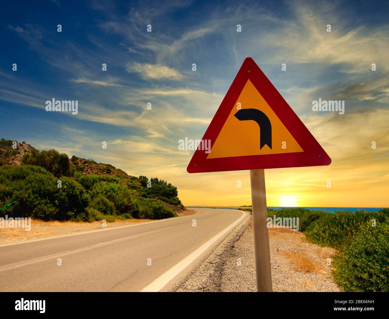 Turn left road sign on a lonely road into sunset in Rhodes. Greece Stock Photo