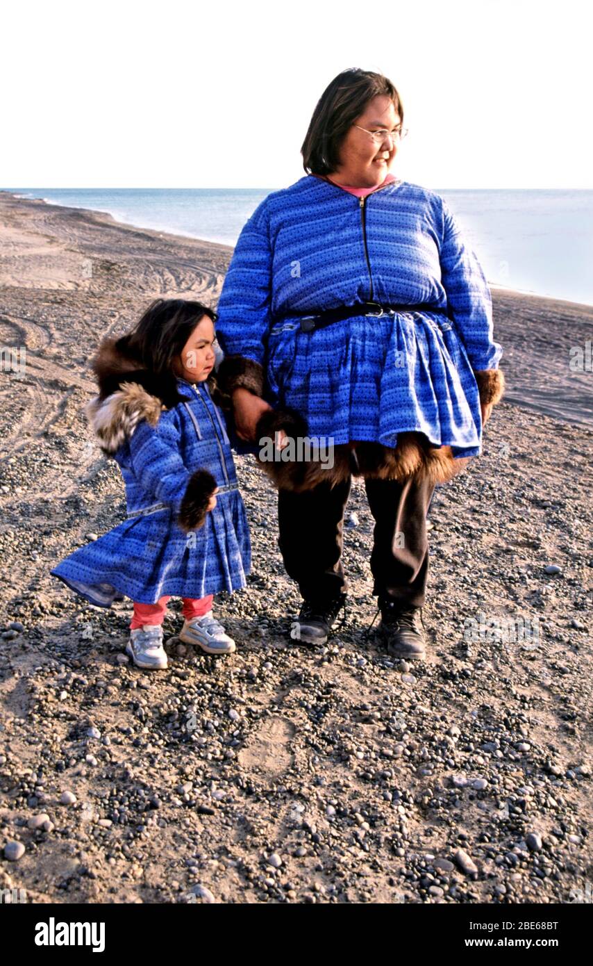 Inupiaq Inuit woman with baby in papoose and toddler in matching jackets on the shore of the Arctic Ocean at 10pm at night, Barrow, Alaska, USA. Stock Photo