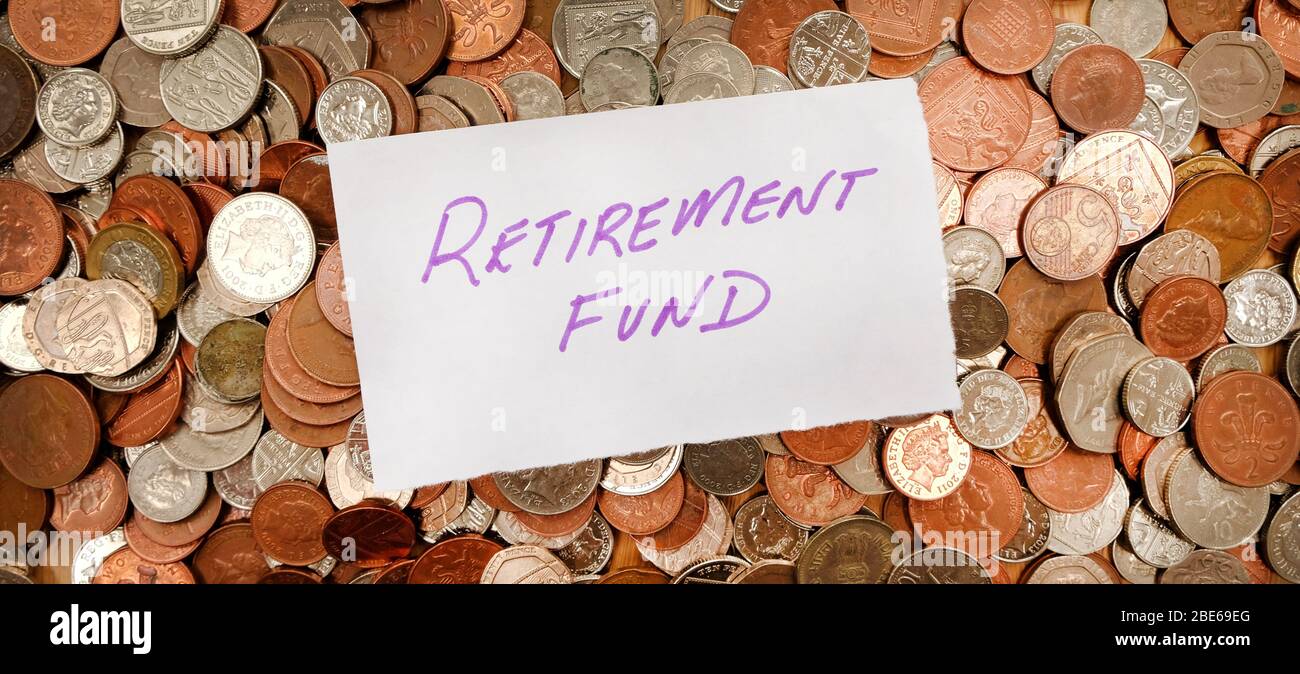 The words retirement fund written in purple pen on white paper, the paper is on top of hundreds of silver and copper coloured British coins Stock Photo