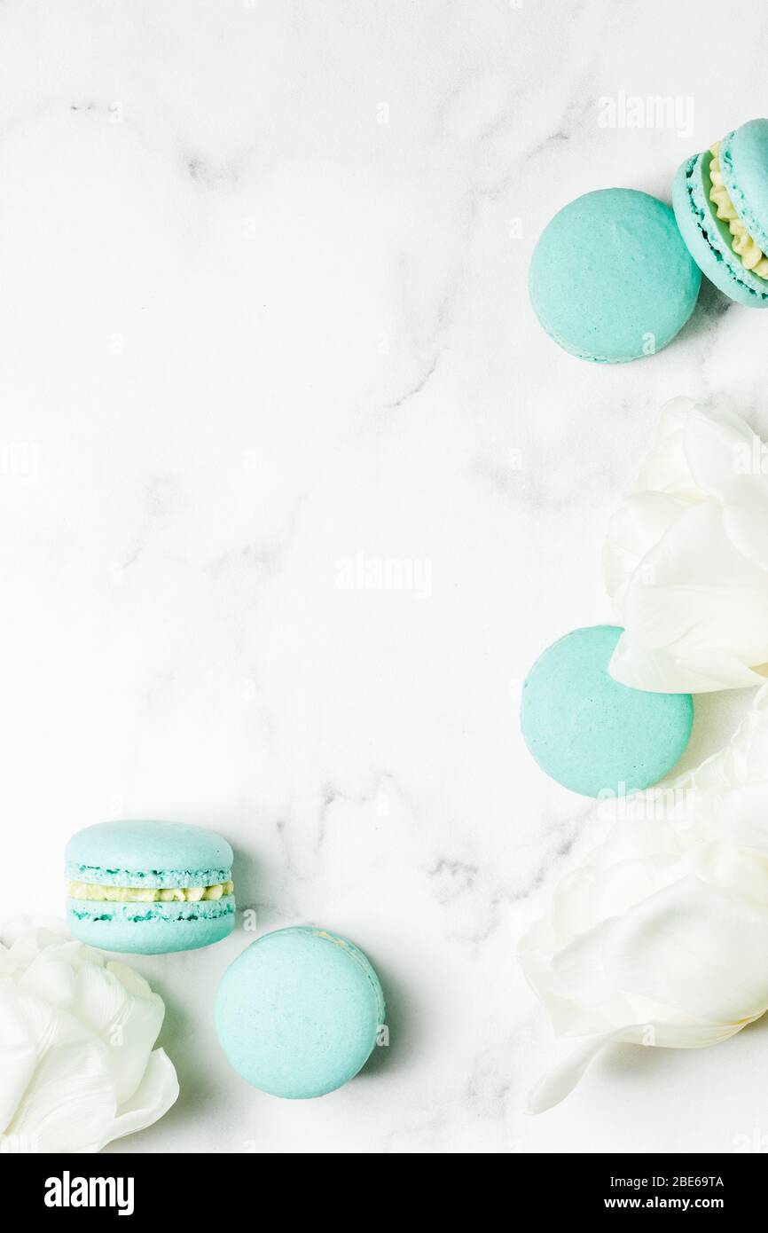 Tulips bouquet with blue macaroon sweeties on bright marble table. Happy Mother's Day concept. Greeting top view background with copy space Stock Photo