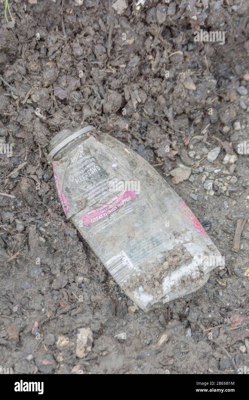 Empty soft drinks bottle on tarmac of a quiet country road. Example of
