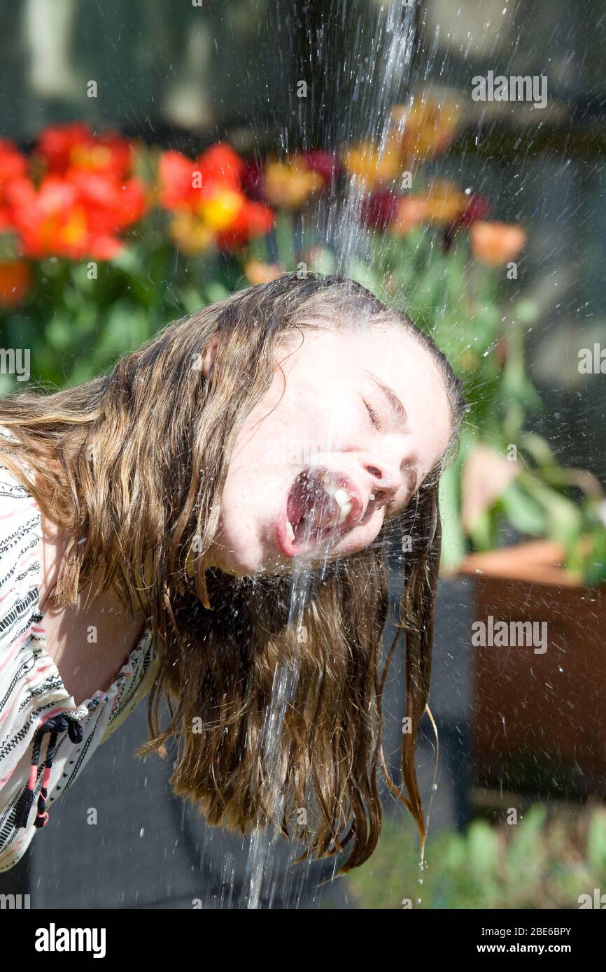 Young girl drinking water from garden hose Stock Photo Alamy