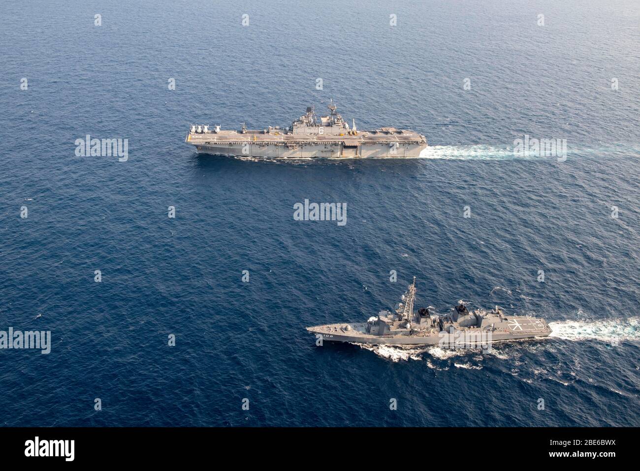 The U.S. Navy flagship America-class amphibious assault ship USS America sails in formation with Japan Maritime Self-Defense Force destroyer JS Akebono, bottom, during routine patrol April 10, 2020 in the East China Sea. Stock Photo