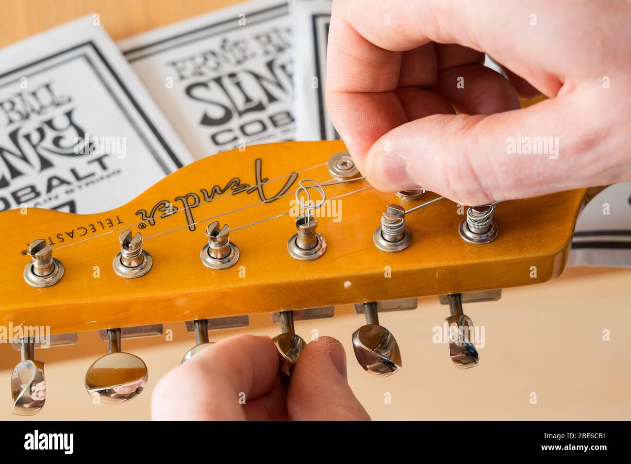 Changing the string on a Fender Modern Player Telecaster electric guitar by removing the string from the vintage tuning post Stock Photo