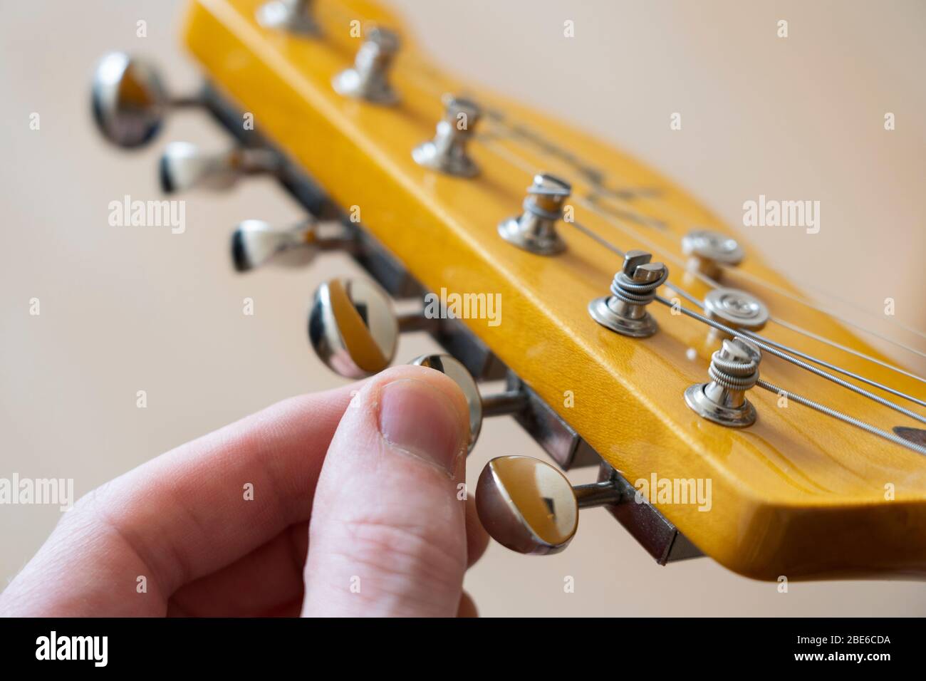 Tuning a Fender Modern Player Telecaster electric guitar by turning a vintage tuning nob on the headstock to tighten / loosen the A string Stock Photo