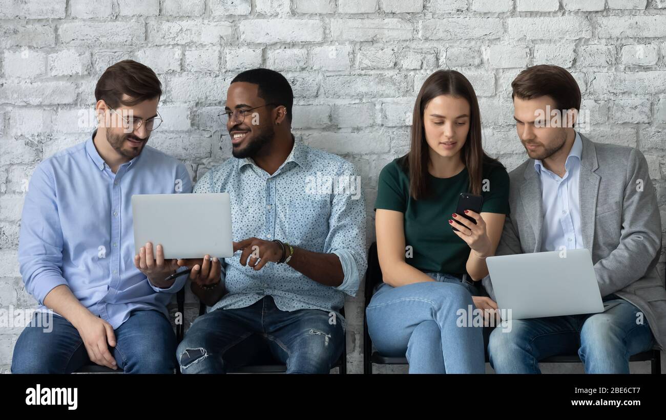 Focused diverse people sit in line using laptops Stock Photo