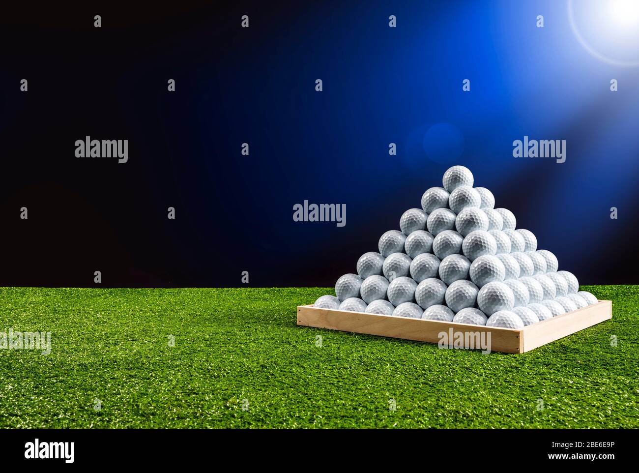 Pyramid of golf balls in a driving range with blue light glow
