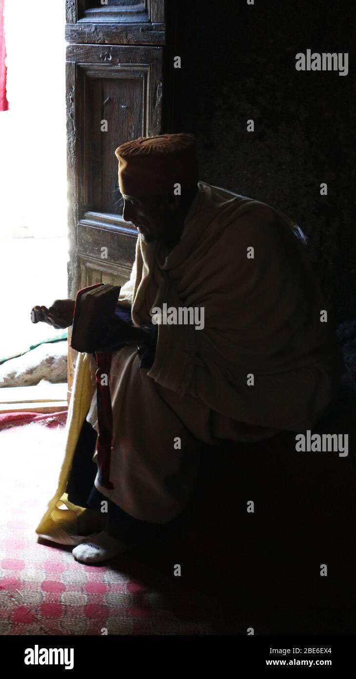 Ethiopian Christian monk in Asheton Maryam Monastery reads the bible by the light of the door Stock Photo