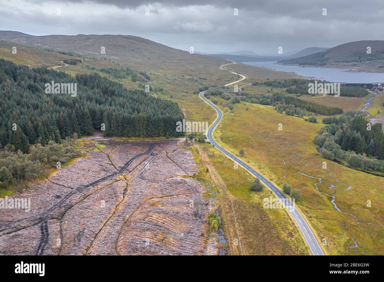 Drone shoot at cloudy autumnal morning over empty asphalt road A87 near Loch Loyne in in the Northwest Highlands of Scotland along North Coast 500 Stock Photo