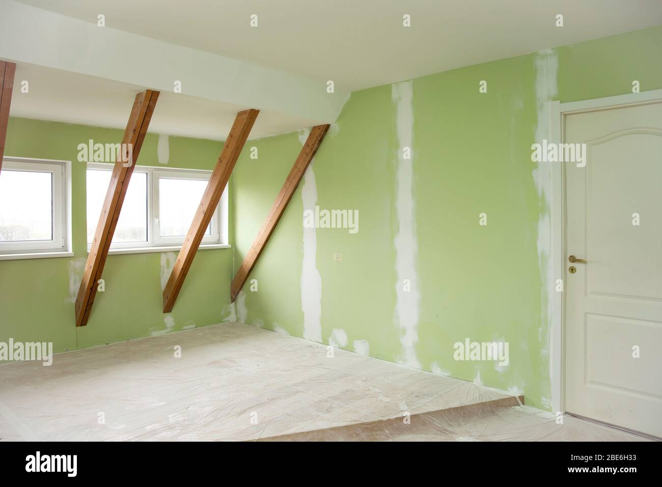 Home renovation work in progress. Repairing old green wall cracks in wall with white new putty. Home renovations concept. Stock Photo