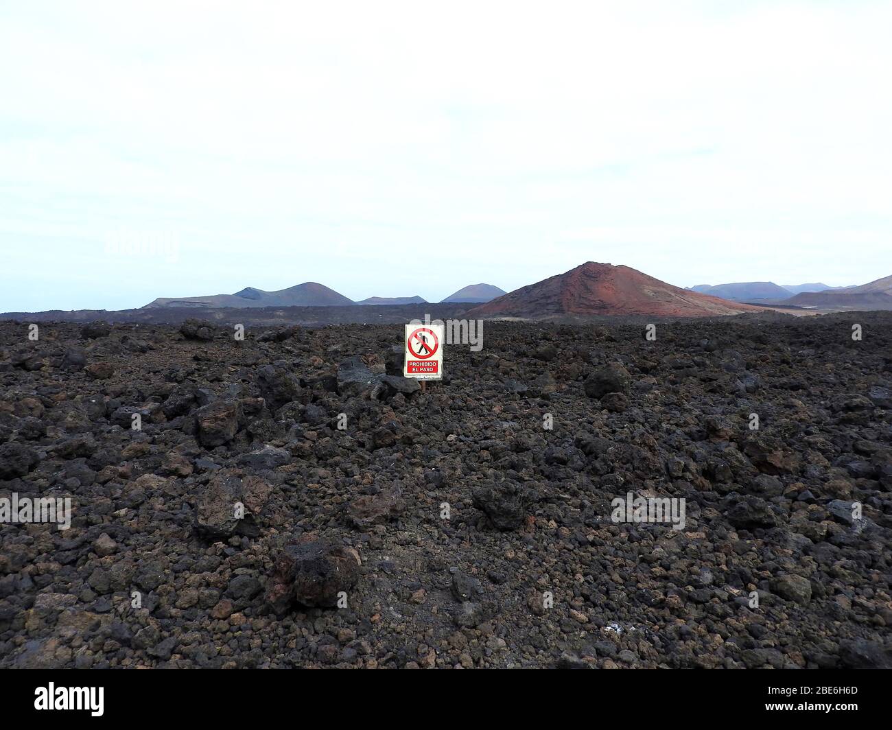 Volcanic landscape of the island of Lanzarote, Canary Islands, Spain - January 2020,  with a sign 'Prohibido el Paso', prohibiting walkers from passing. Stock Photo