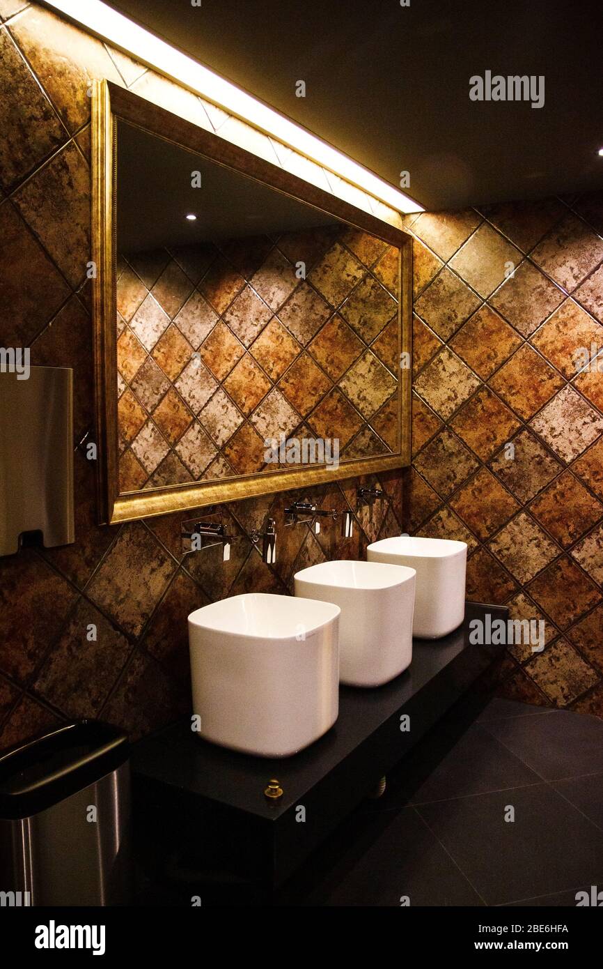 Golden brown design water closet room with bronze color tile on a wall and big mirror three
