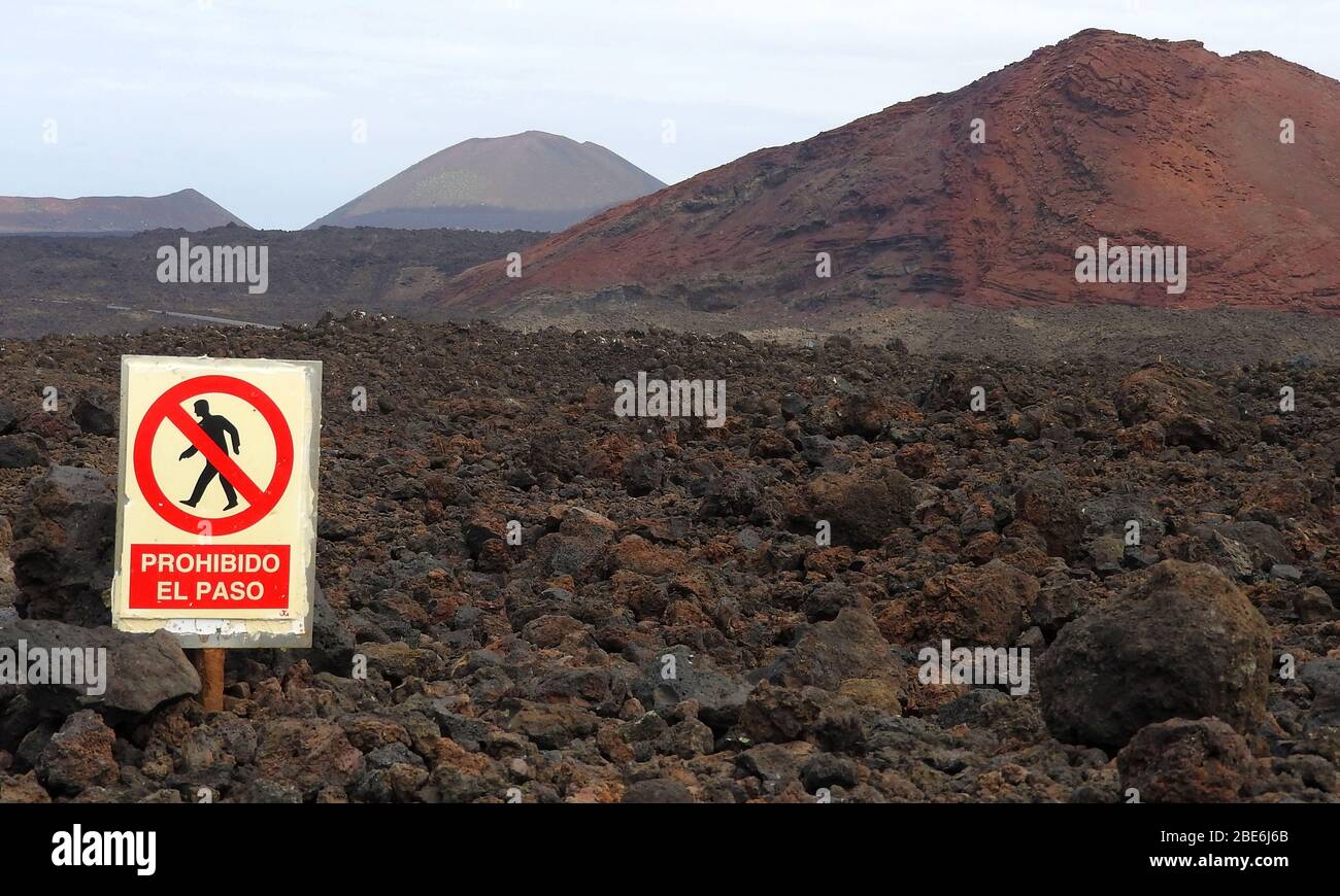 Volcanic landscape on the island of Lanzarote, Canary Islands, Spain - January 2020,  with a sign 'Prohibido el Paso', prohibiting walkers from passing and walking onto the volcanic lava rocks Stock Photo