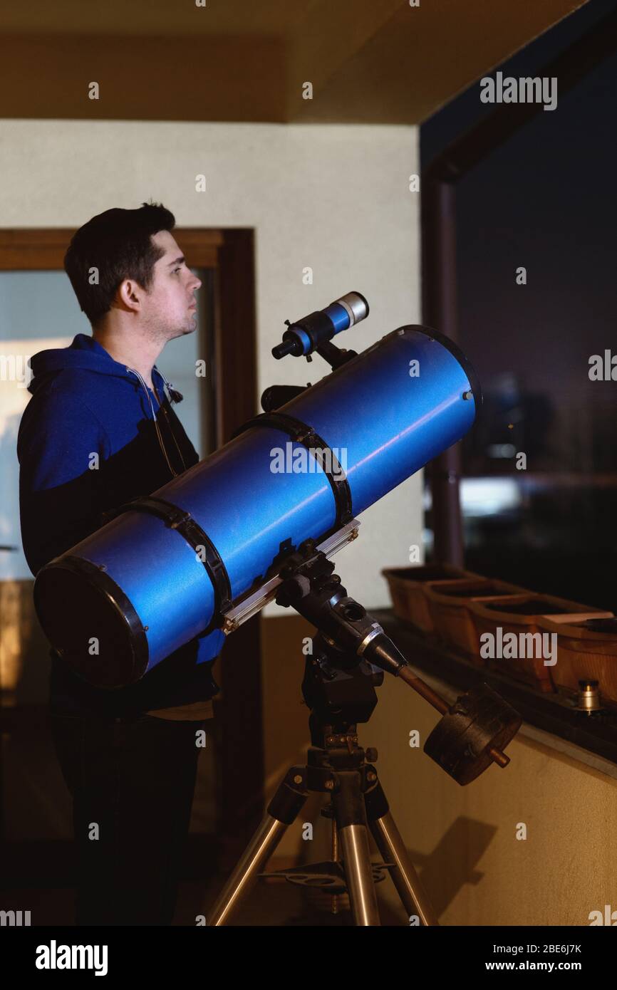 Man looking at stars through telescope on balcony Stock Photo Alamy