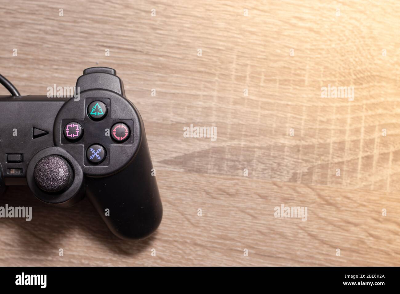 Half of a console video gaming controller on the left on wooden grey brown  background. Cable rolled up in a ball , concept of gaming Stock Photo -  Alamy