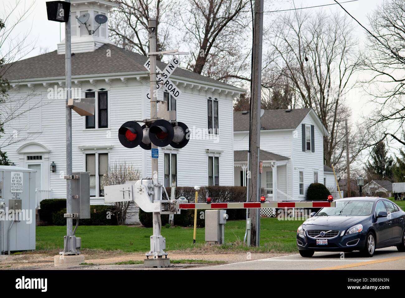 LaFox, Illinois, USA. A just descended road crossing gate with flashing red lights warns motorists of an upcoming freight train. Stock Photo