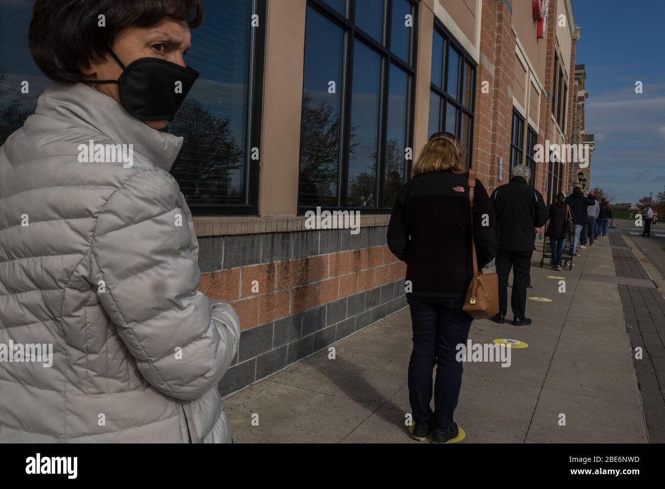 Covid-19, long line of face-masked people waiting to enter a food market in suburban Philadelphia, PA, April 11, 2020 Stock Photo