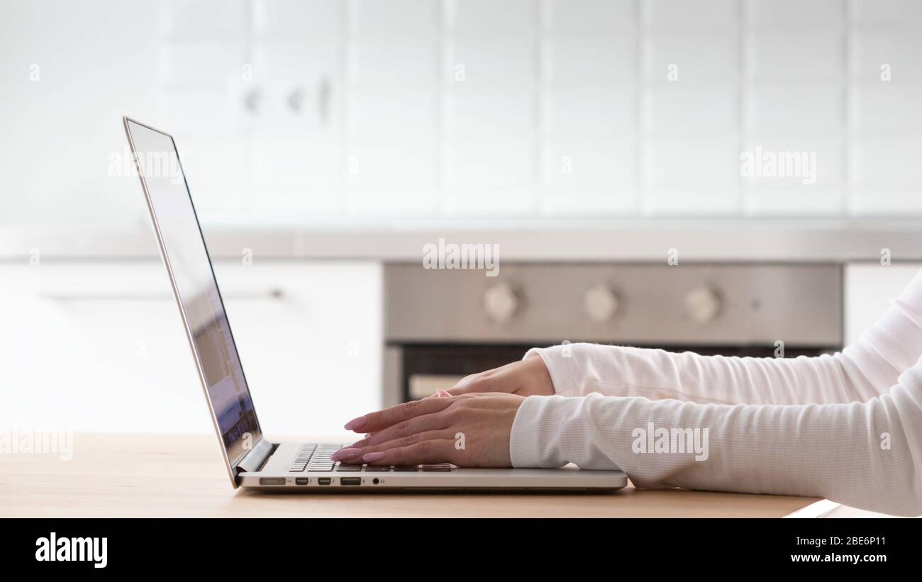 Close up of woman hands using and typing on laptop keyboard on wooden table at home office. Stock Photo
