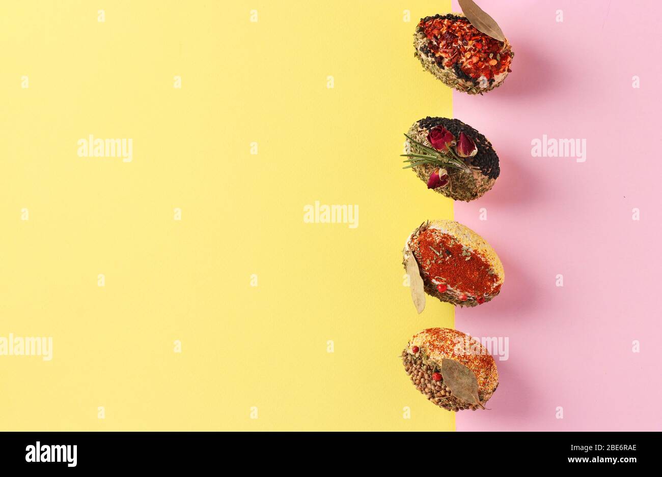 Easter concept with eggs decorated with different spices and cereals without dyes and preservatives on pink and yellow background, Copy space Stock Photo