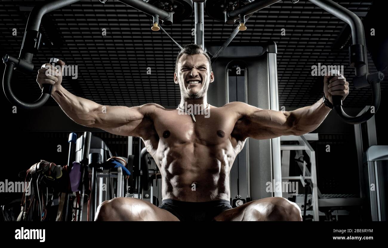brawny guy bodybuilder, execute exercise on gym apparatus exercise machine butterfly in gym Stock Photo