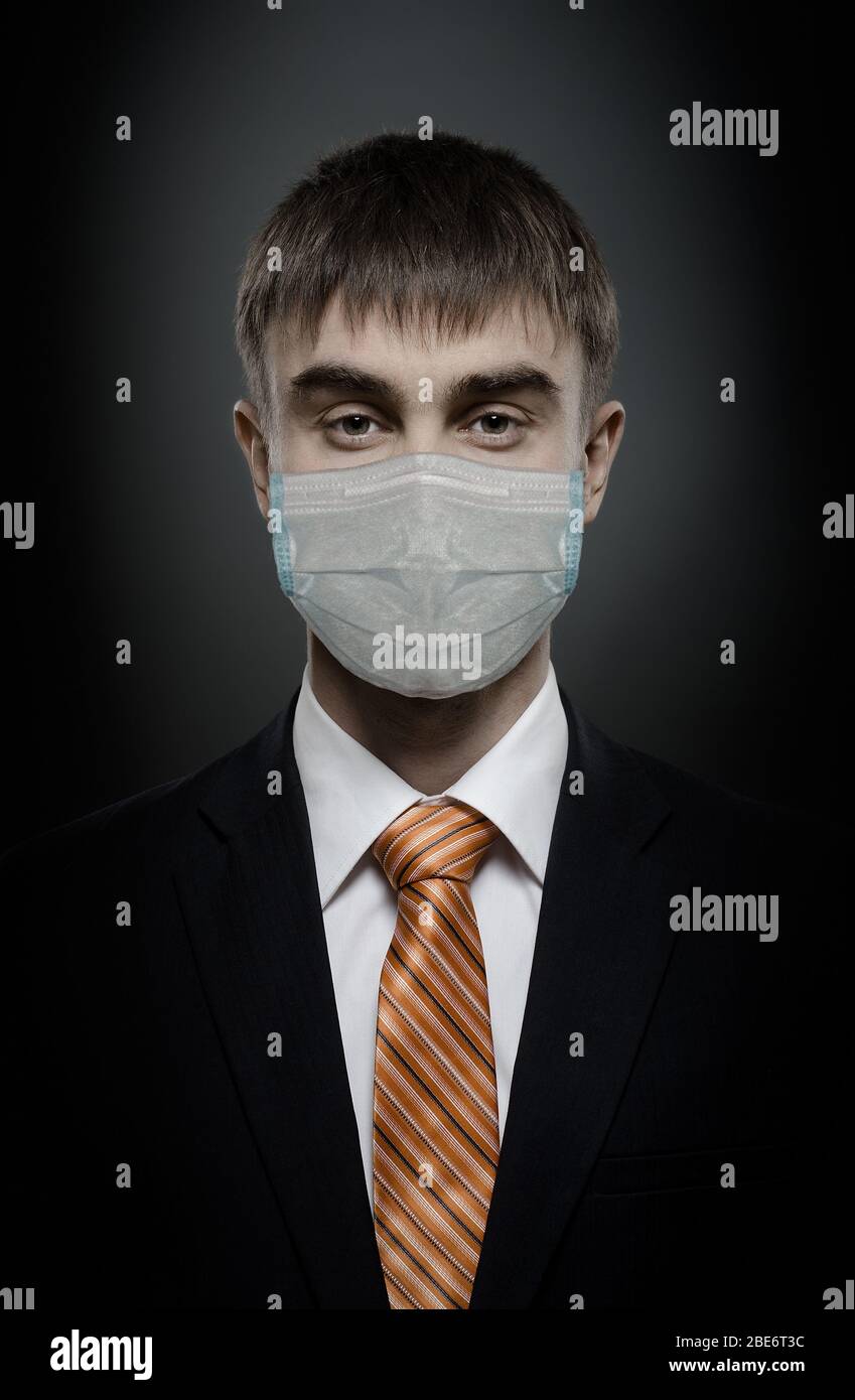 concept coronavirus epidemic, portrait businessman in medical mask, black costume and orange necktie, face closeup, Stock Photo