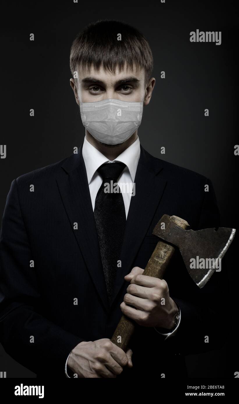 coronavirus epidemic concept, portrait man in medical mask with axe Stock Photo
